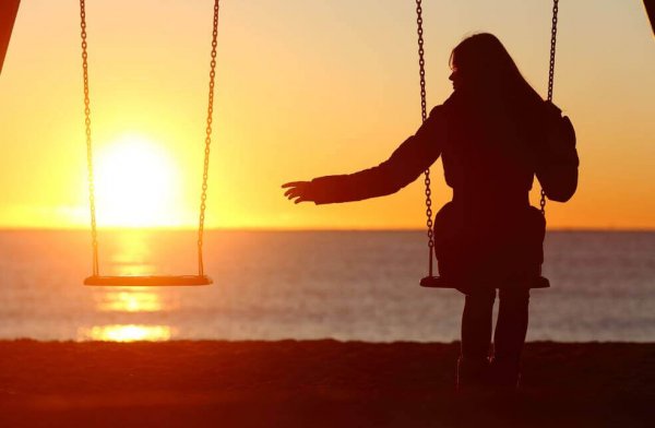 夕暮れにブランコに乗る女性