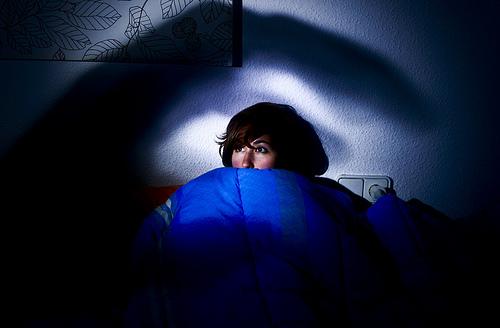 ベッドの中で怖がる女性