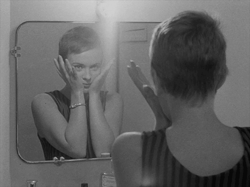 鏡の前で顔を覆う女性