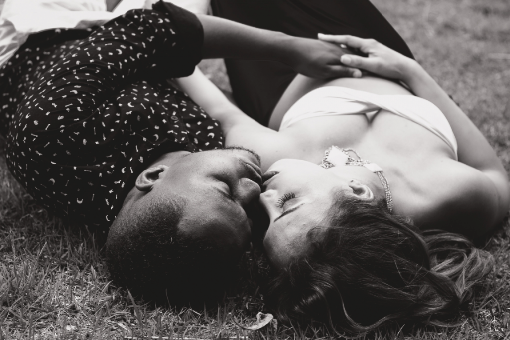 草原に寝そべってキスするカップル