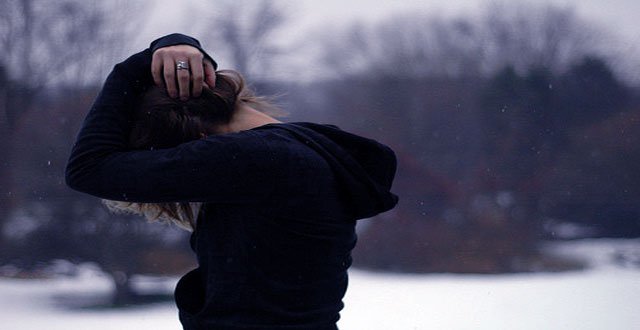 雪の中で頭を抱える女性