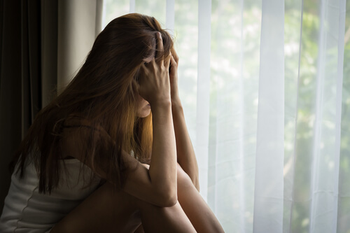 窓辺で頭を抱える女性