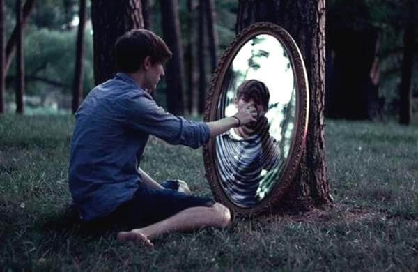 鏡の中に手を伸ばす少年