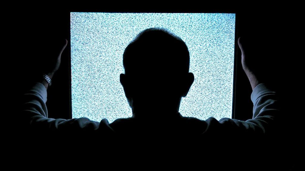 白黒のテレビ画面を見る男性