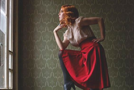 窓辺でポーズをとる赤いスカートの女性