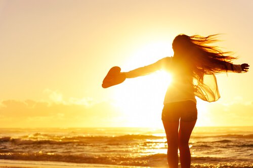 夕暮れの海辺に立つ女性