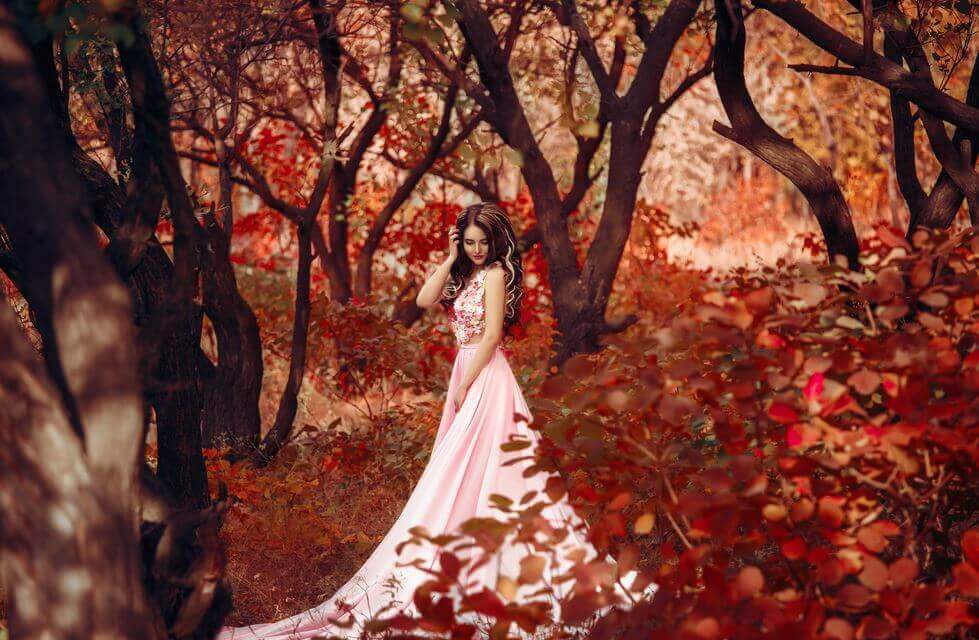 秋の森に立つドレスの女性