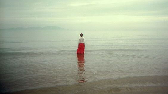 水の中を歩く赤いスカートの女性