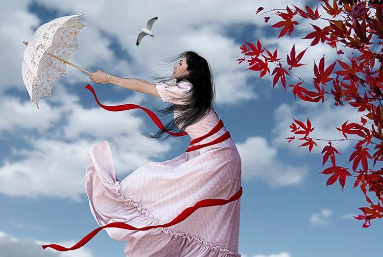 日傘が風に吹かれる女性