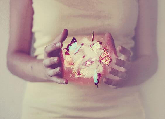 両手の間に蝶が飛ぶ女性