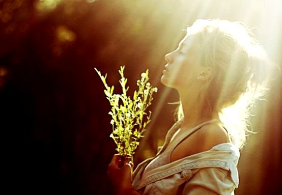 手に草を持った日の中の女性