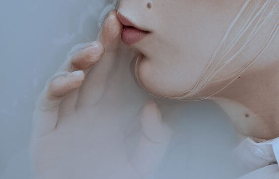 唇に指をあてた女性の横顔