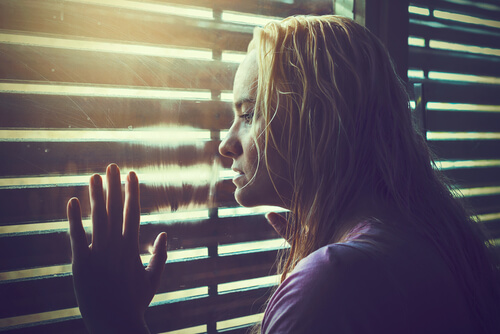 ブラインドの外を見る女性