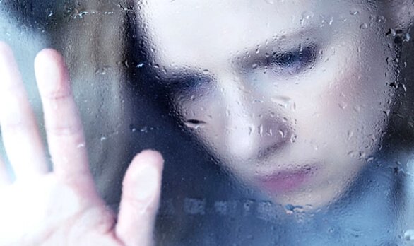 窓に手を当てる女性