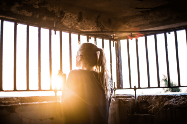 鉄格子の外を見る女性 ネガティブな感情