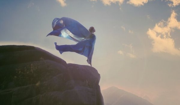 崖っぷちに立つ青いドレスの女性