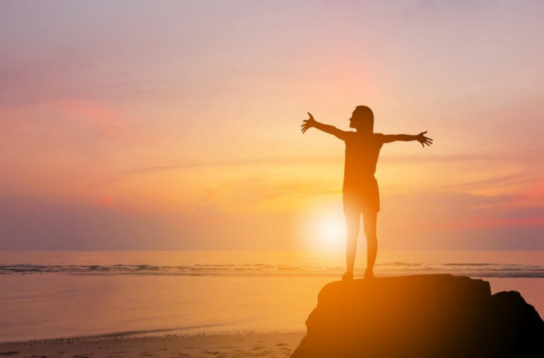 夕日に両手を広げる女性