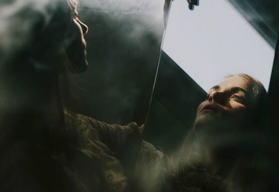 反射した自分を見つめる女性