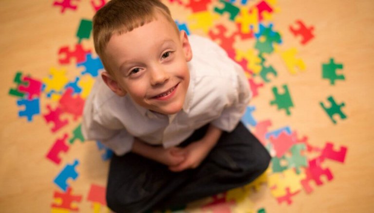 自閉症の子供がパズルの上で笑う