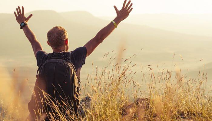 両手を挙げるバッグパッカー