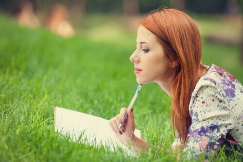 芝生で日記をつける女性