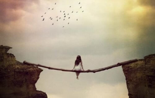 崖に渡された木に座る女性