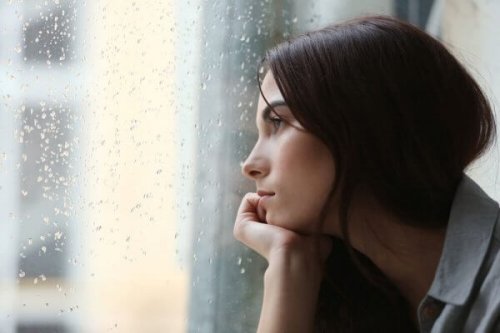 窓の外の雨を見つめる女性